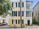 Three story yellow house with black shutters, white columns and a gated courtyard at 53 Hasell Street St # H, Charleston, SC 29401