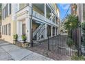 Gated courtyard entrance to a charming yellow house with white columns and brick driveway at 53 Hasell Street St # H, Charleston, SC 29401