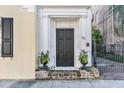 Dark wood front door with sidelights, flanked by planters, and a brick stoop at 53 Hasell Street St # H, Charleston, SC 29401