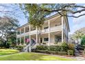 Grand two-story home with wrap-around porch, mature trees, and manicured lawn at 1738 Ion Ave, Sullivans Island, SC 29482