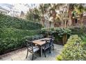 Outdoor patio with wooden dining table and chairs, surrounded by greenery at 99 Tradd St, Charleston, SC 29401