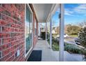 Covered front porch with brick flooring and white columns at 7963 Shadow Oak Dr, North Charleston, SC 29406