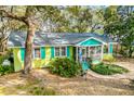 Quaint yellow cottage with teal trim, nestled among mature trees at 10 Chapman Ave, Isle of Palms, SC 29451