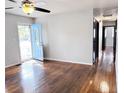 Bright living room featuring hardwood floors, a ceiling fan, and a charming light blue front door at 227 Bailey St, Walterboro, SC 29488