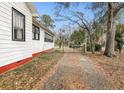 View of home's side and gated driveway with mature trees and landscaping at 222 E Main St, Moncks Corner, SC 29461