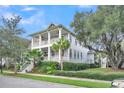 Charming two-story home featuring double porches, a landscaped yard with palm trees, and a classic coastal design at 164 River Green Pl, Charleston, SC 29492