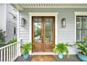 Inviting front entrance showcasing a beautiful wood double door, stylish sconces, and lush potted plants at 164 River Green Pl, Charleston, SC 29492