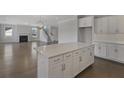 Bright kitchen with white cabinets, an island, and hardwood floors, leading to the living room and staircase at 2006 Riverbend Dr, Charleston, SC 29412