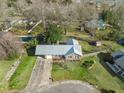 An aerial view of a brick home with well-maintained landscaping, a long driveway, and mature trees at 305 Meadowlark Ln, Moncks Corner, SC 29461