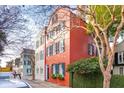 Exterior street view showcases the red brick home with its colorful shutters and landscaping at 32 Tradd St, Charleston, SC 29401