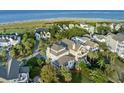 Expansive aerial shot showcasing a luxury home with a waterfront view and access to a pristine beach at 10 Ocean Point Dr, Isle of Palms, SC 29451