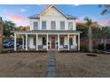 Charming white farmhouse with a covered porch, perfect for enjoying serene evenings at 1119 Simmons St, Mount Pleasant, SC 29464