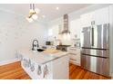 Modern kitchen with a marble island, stainless steel appliances, white cabinetry, and hardwood flooring, illuminated by a stylish light fixture at 22 1/2 Mary St # A B C, Charleston, SC 29403