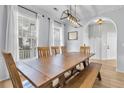 Bright dining room with a large wooden table, modern light fixture, and large windows with bright natural light at 1821 Great Hope Dr, Mount Pleasant, SC 29466