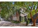 Beautiful brick home with lush greenery, palm trees, and sidewalk access on a sunny day at 23 Elliott St, Charleston, SC 29401
