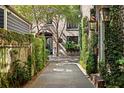 Picturesque walkway with stone pavers lined by verdant greenery leading towards a black iron gate at 23 Elliott St, Charleston, SC 29401