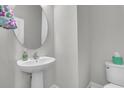 Powder room with pedestal sink, round mirror, modern fixtures, and a comfort height toilet at 3066 Emma Ln, Mount Pleasant, SC 29466