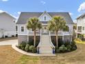 Inviting coastal home with grand staircase, a welcoming porch, lush landscaping and a delightful curb appeal at 4258 Jacobs Pt Ct, Ravenel, SC 29470