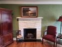Close up on the living room brick fireplace with mantel and hearth, with decorative furniture and hardwood floors at 1216 Eastwood Ave, Hanahan, SC 29410