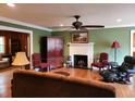 Cozy living room boasts a classic fireplace, a ceiling fan, hardwood floors, and a view to the dining room at 1216 Eastwood Ave, Hanahan, SC 29410
