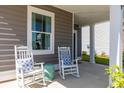Inviting front porch with rocking chairs, a small table, and a view of the well-maintained lawn at 131 Threaded Fern St, Summerville, SC 29485