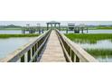 Picturesque wooden dock leading to boat lifts on calm waters with lush green shoreline at 1618 Folly Creek Way # B2, Charleston, SC 29412