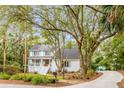 Charming two-story home with a light gray exterior, blue shutters, and mature trees at 23 Edgewater Aly, Isle of Palms, SC 29451