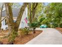 Side view of a light gray two-story home with green landscaping and a private driveway at 23 Edgewater Aly, Isle of Palms, SC 29451