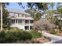 Attractive two-story home featuring a welcoming porch, wood finishes, and mature trees at 707 Glossy Ibis Ln, Kiawah Island, SC 29455