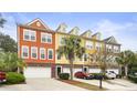 A row of colorful townhomes with attached garages, palm trees, and well-maintained landscaping at 9309 Sweetbay Ct, Ladson, SC 29456