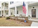 Close-up of inviting front porch with seating, American flag, and well-maintained landscaping at 129 Sabal Ct, Summerville, SC 29483