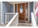 Elegant wood front door with glass inserts and a white porch railing, enhancing curb appeal at 2653 Seabrook Island Rd, Seabrook Island, SC 29455