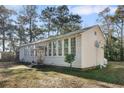 Exterior side view showcasing the home's window lined walls and the surrounding mature trees, and landscaped yard at 4680 Bears Bluff Rd, Wadmalaw Island, SC 29487