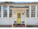 Inviting front entrance features a sunny yellow door, hanging lanterns, and charming decor, enhancing curb appeal at 4680 Bears Bluff Rd, Wadmalaw Island, SC 29487