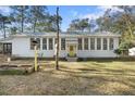 Beautiful front exterior showcasing a bright yellow door, a manicured lawn, and mature trees adding charm to the home at 4680 Bears Bluff Rd, Wadmalaw Island, SC 29487