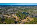 Aerial view of an estate with a pond and multiple buildings, surrounded by lush, mature trees at 120 Rancho Hippey Way, Saint George, SC 29477