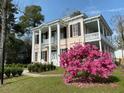 Charming two-story home with columns, balconies and flowering bush at 301 E Richardson Ave, Summerville, SC 29483