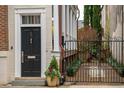 Elegant front entrance with a black door, white trim, gated entry and lush plantings at 31 Hasell St, Charleston, SC 29401