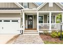 Close-up of the front porch featuring a welcome sign, hanging swing, and brick pathway at 1502 Checker Ct, Mount Pleasant, SC 29466
