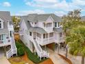 Three story elevated beach home with wrap-around porch, lush greenery, and mature trees at 1607 Folly Creek Way Way # C-5, Charleston, SC 29412