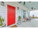 Relaxing front porch showcases a vibrant red door, stylish decor, and comfortable seating area at 1702 Sparkleberry Ln, Johns Island, SC 29455