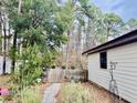 A fenced in back yard with a stone path and an array of trees and plants at 204 Chamblee Rd, Walterboro, SC 29488