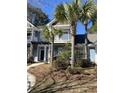 Charming two-story blue townhome featuring a pergola-covered entrance and surrounded by lush palm trees at 2905 Sweetleaf Ln, Johns Island, SC 29455