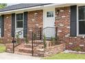 Close-up of the home's brick facade, steps, and entryway featuring black shutters at 2916 Marginal Rd, Charleston, SC 29414