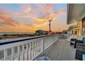 Scenic porch view with chairs overlooking the ocean and a vibrant sunset sky at 407 Palmetto Blvd, Edisto Beach, SC 29438