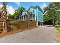 Beautiful home exterior featuring a wood fence, palm trees, and lush green foliage at 112 E Huron Ave # C, Folly Beach, SC 29439