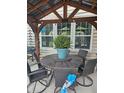 Outdoor dining area beneath a pergola, featuring a round table, swivel chairs, and potted ferns at 1915 Sweetfern Rd, Hanahan, SC 29410