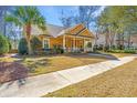 Charming yellow home with a welcoming front porch surrounded by lush landscaping and a palm tree at 297 Hundred Oaks Pkwy, Summerville, SC 29483