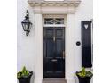 Elegant front door featuring fluted columns, transom window, and decorative black flower pots at 35 Tradd St, Charleston, SC 29401