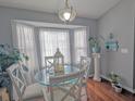 Bright dining area with modern light fixture, stylish glass table, seating for four, and bright natural lighting at 409 Reserve Way, Summerville, SC 29485